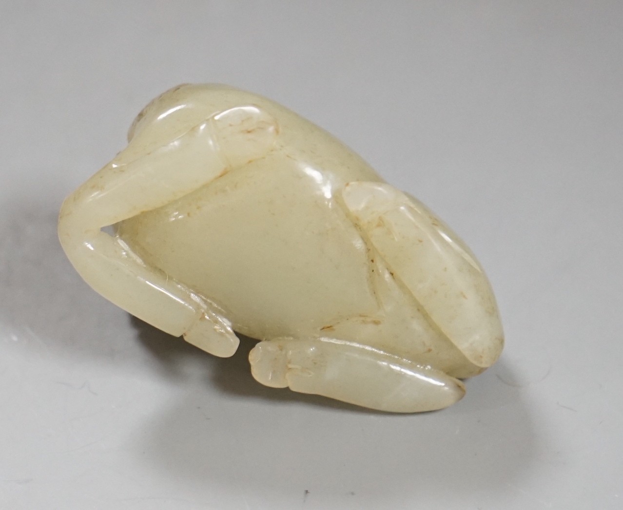 A 19th century Chinese pale celadon jade figure of a seated horse, 6cm wide